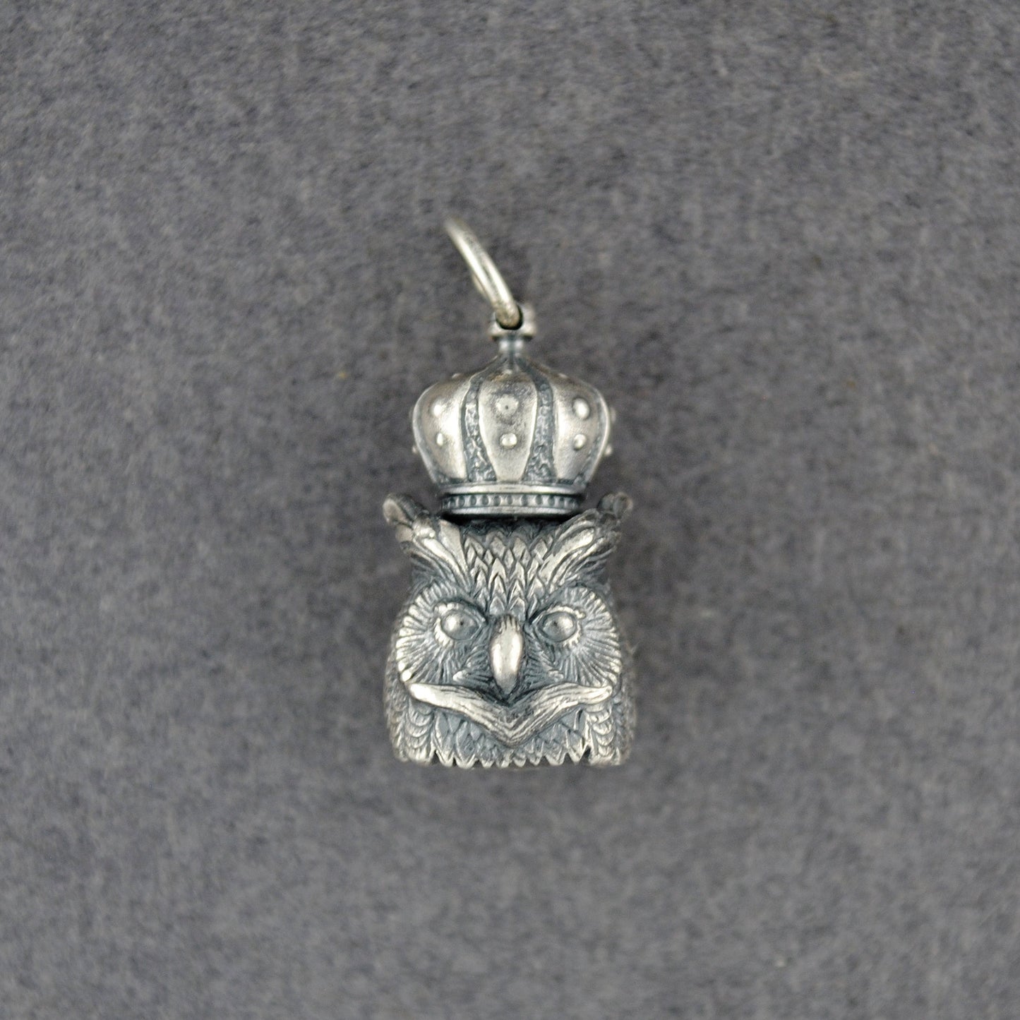 Silver owl pendant with a crown on a gray background
