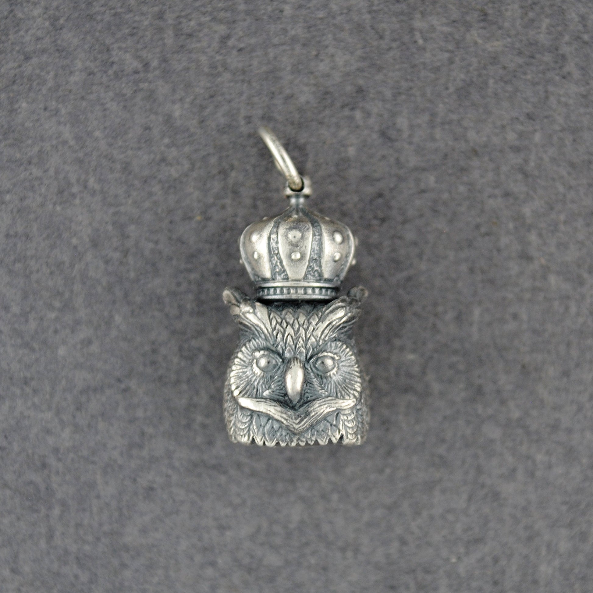 Silver owl pendant with a crown on a gray background