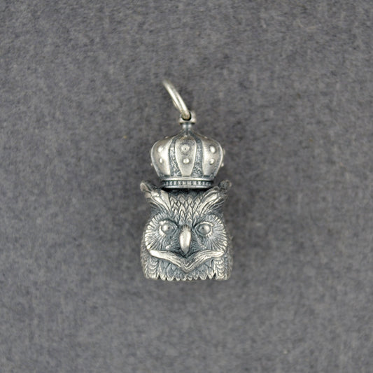 Silver owl pendant with a crown on a gray background