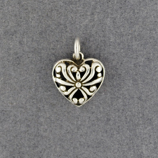 Silver heart-shaped pendant with intricate design on a gray background